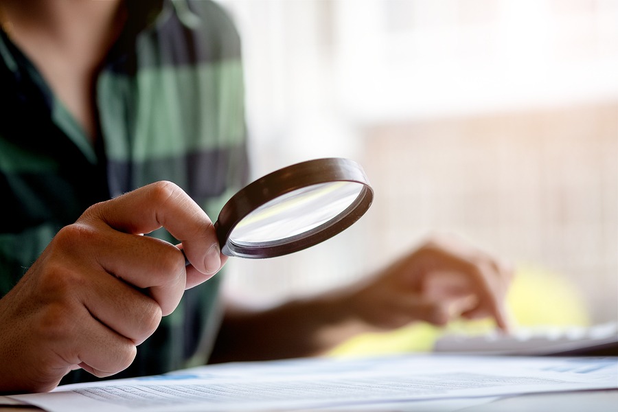 Businessman Looking Through A Magnifying Glass To Documents