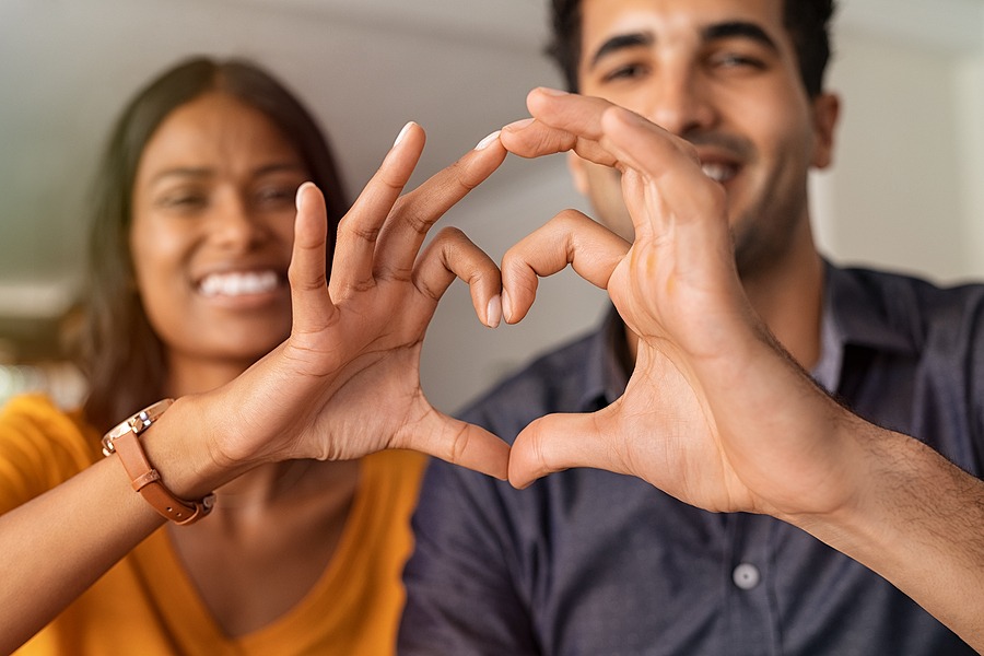 Close up of middle eastern couple making heart shape with hands.
